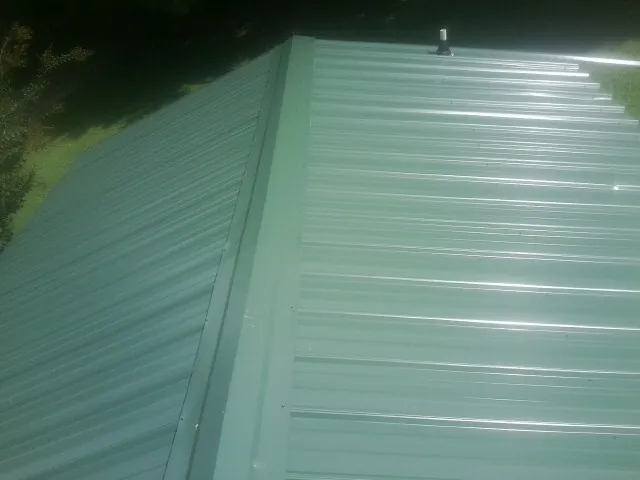 New green metal panels meeting at the ridge of a roof — Flat Roof Repair work by our crew in Carson