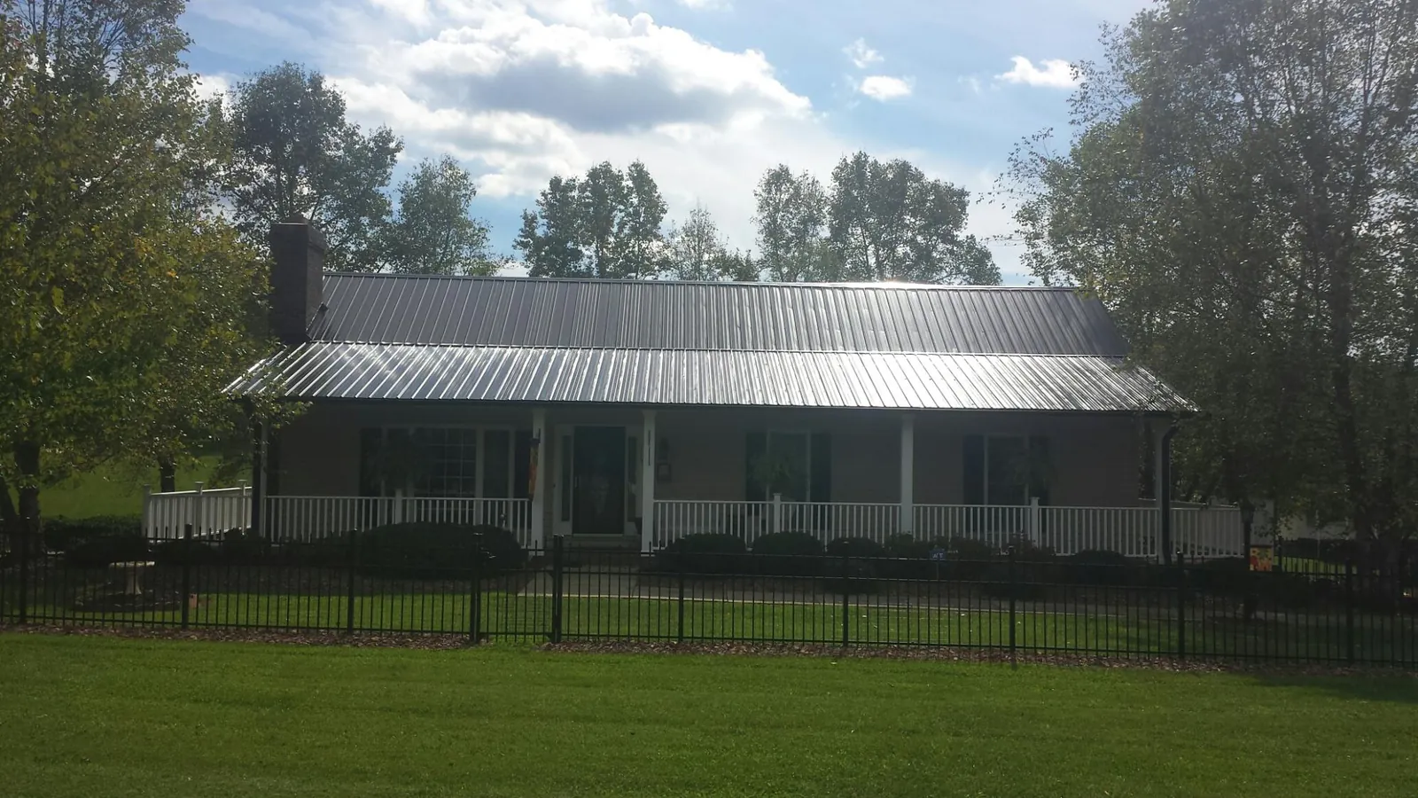 Gray metal roof on a brick ranch with a full width front porch — Gutter Guard Installation work by our crew in Carson